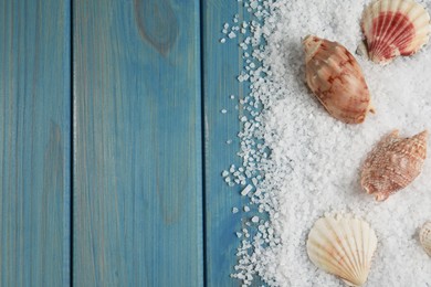 Photo of Beautiful shells with natural sea salt on light blue wooden table, flat lay. Space for text