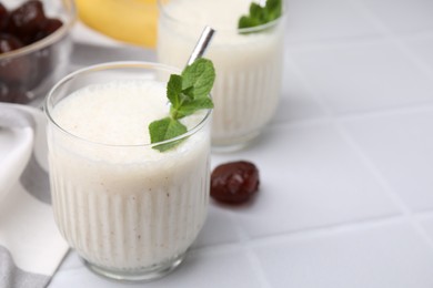 Photo of Glass of delicious date smoothie with mint on white table, closeup. Space for text