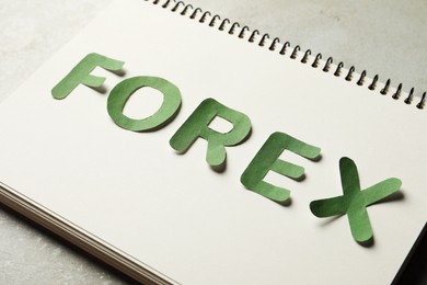 Notebook with word Forex made of green letters on grey table