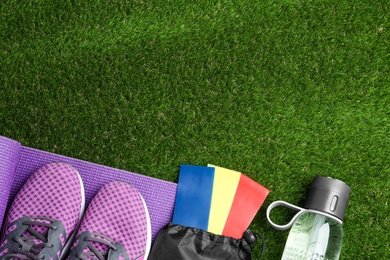 Photo of Flat lay composition with fitness elastic bands on green grass. Space for text