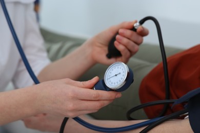 Doctor checking blood pressure of man in clinic, closeup