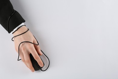 Photo of Internet addiction. Top view of man using computer mouse on white background, hand tied with cable