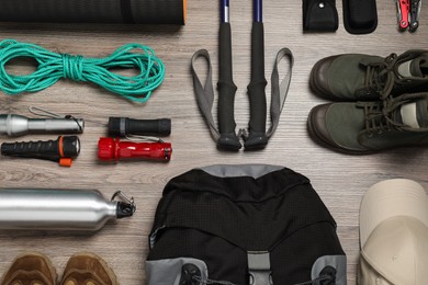 Photo of Flat lay composition with trekking poles and other hiking equipment on wooden background