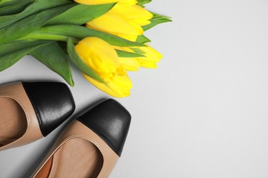 Photo of Pair of new stylish square toe ballet flats and beautiful tulips on light grey background, flat lay. Space for text