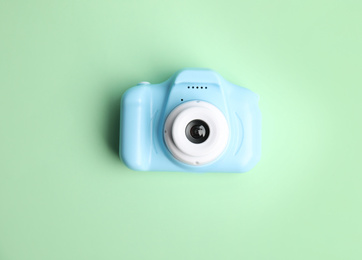 Light blue toy camera on light green background, top view. Future photographer