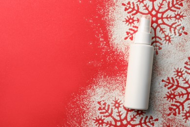 Photo of Winter skin care. Hand cream and snowflake silhouettes made with artificial snow on red background, top view. Space for text