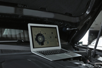 Photo of Laptop with diagram on auto engine. Modern car diagnostic
