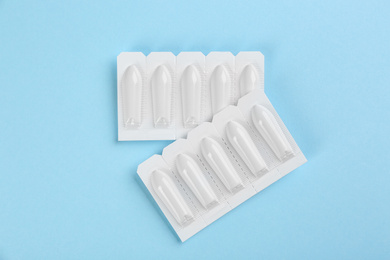 Suppositories on light blue background, flat lay. Hemorrhoid treatment