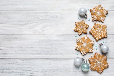 Tasty Christmas cookies and baubles on white wooden table, flat lay. Space for text
