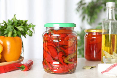 Glass jar of pickled pickled peppers on white table