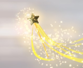 Beautiful golden wand and shiny magical dust on light background