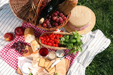 Blanket with different products on green grass, top view. Summer picnic
