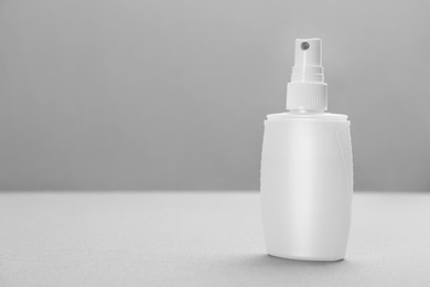 Bottle with insect repellent spray on grey background, space for text