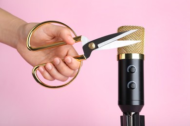 Woman making ASMR sounds with microphone and scissors on pink background, closeup