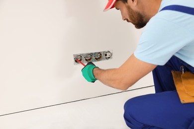 Photo of Electrician with screwdriver repairing power sockets indoors