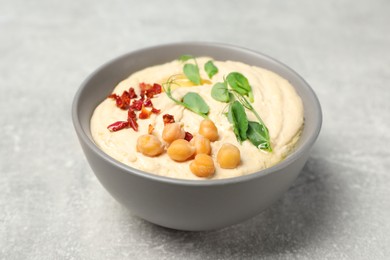 Tasty hummus with garnish in bowl on grey table