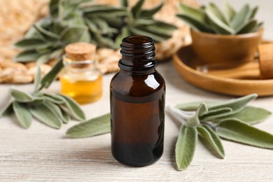 Bottle of essential sage oil and leaves on wooden table