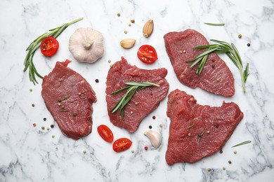 Fresh raw meat steaks and spices on white marble table, flat lay