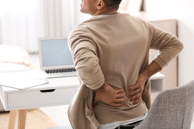 Photo of Man suffering from back pain at table, closeup. Bad posture problem