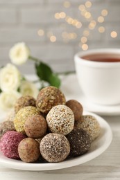 Delicious vegan candy balls on white wooden table against blurred lights