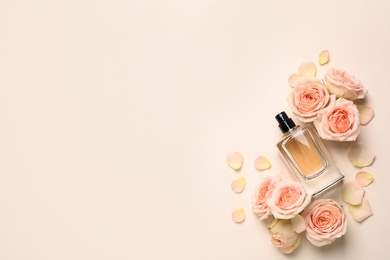 Flat lay composition with bottle of perfume and roses on light background, space for text