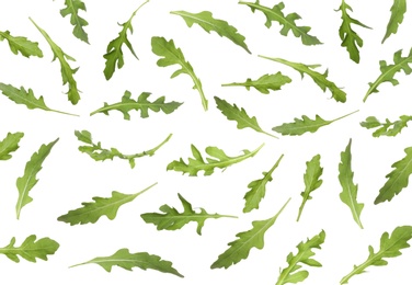 Many green arugula leaves falling on white background