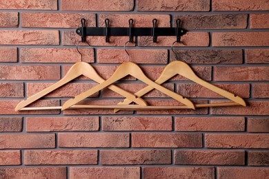Photo of Hook rack with wooden clothes hangers on red brick wall