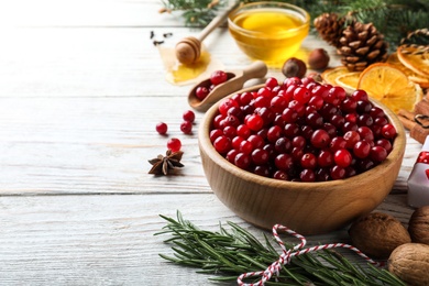 Photo of Fresh ripe cranberries, spices and products on white wooden table. Space for text
