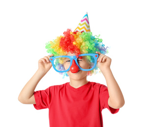 Little boy in clown wig, party hat and funny glasses on white background. April fool's day