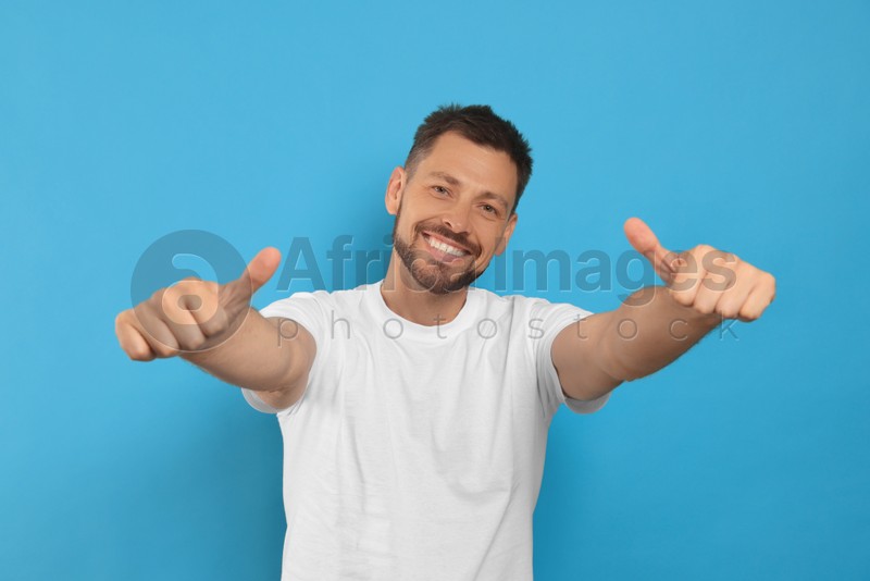 Man showing thumbs up on light blue background