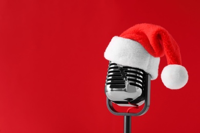 Retro microphone with Santa hat on red background, space for text. Christmas music