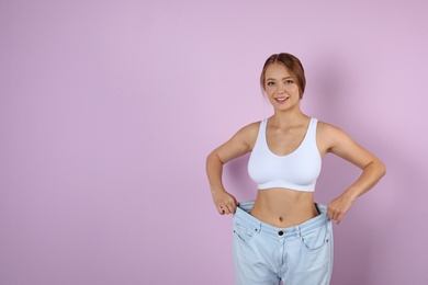 Young woman wearing oversize pants on color background. Healthy diet