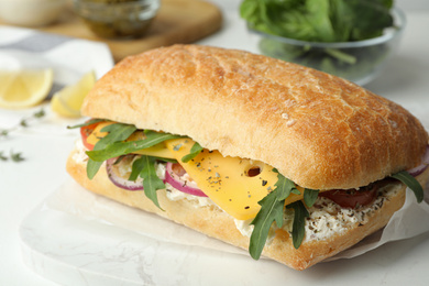 Photo of Delicious sandwich with fresh vegetables and cheese on white table, closeup