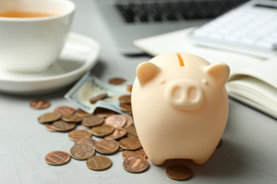 Photo of Piggy bank and money on light grey table, closeup. Space for text