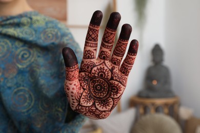Woman with henna tattoo on palm indoors, closeup. Traditional mehndi ornament