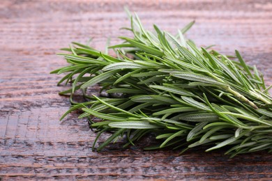 Fresh green rosemary twigs on wooden table, closeup