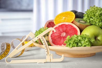 Body fat caliper, measuring tape, vegetables and fruits on table. Diet plan from nutritionist