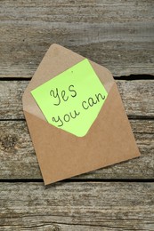 Envelope and phrase Yes You Can on wooden table, top view. Motivational quote