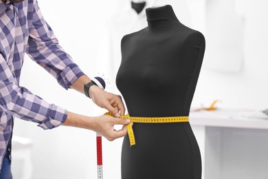 Photo of Tailor measuring mannequin in workshop, closeup