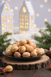 Photo of Homemade walnut shaped cookies with boiled condensed milk near fir branches on wooden table. Bokeh effect