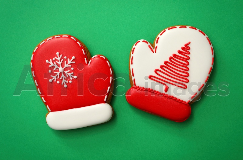 Christmas mitten shaped gingerbread cookies on green background, flat lay