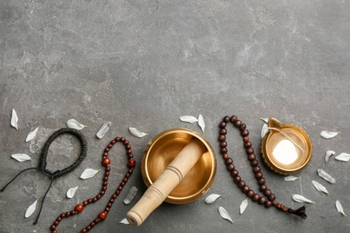 Flat lay composition with golden singing bowl on grey stone table, space for text. Sound healing