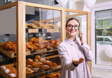Photo of Female business owner talking on mobile phone in bakery
