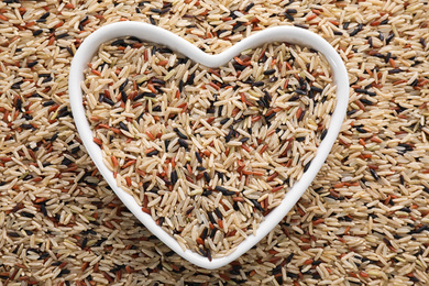 Mix of different brown rice and heart shaped bowl, top view