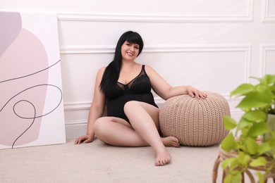 Beautiful overweight woman in black underwear posing at home. Plus-size model