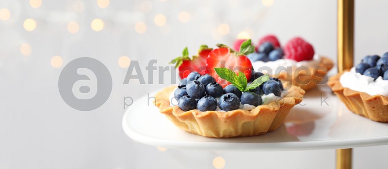 Tarts with different berries on cake stand, space for text. Banner design