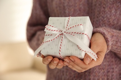 Woman holding white Christmas gift box indoors, closeup