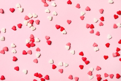 Heart shaped sprinkles on pink background, flat lay