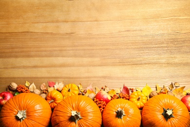 Flat lay composition with ripe pumpkins and autumn leaves on wooden table, space for text. Happy Thanksgiving day