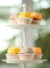 Photo of Dessert stand with tasty cupcakes indoors, closeup